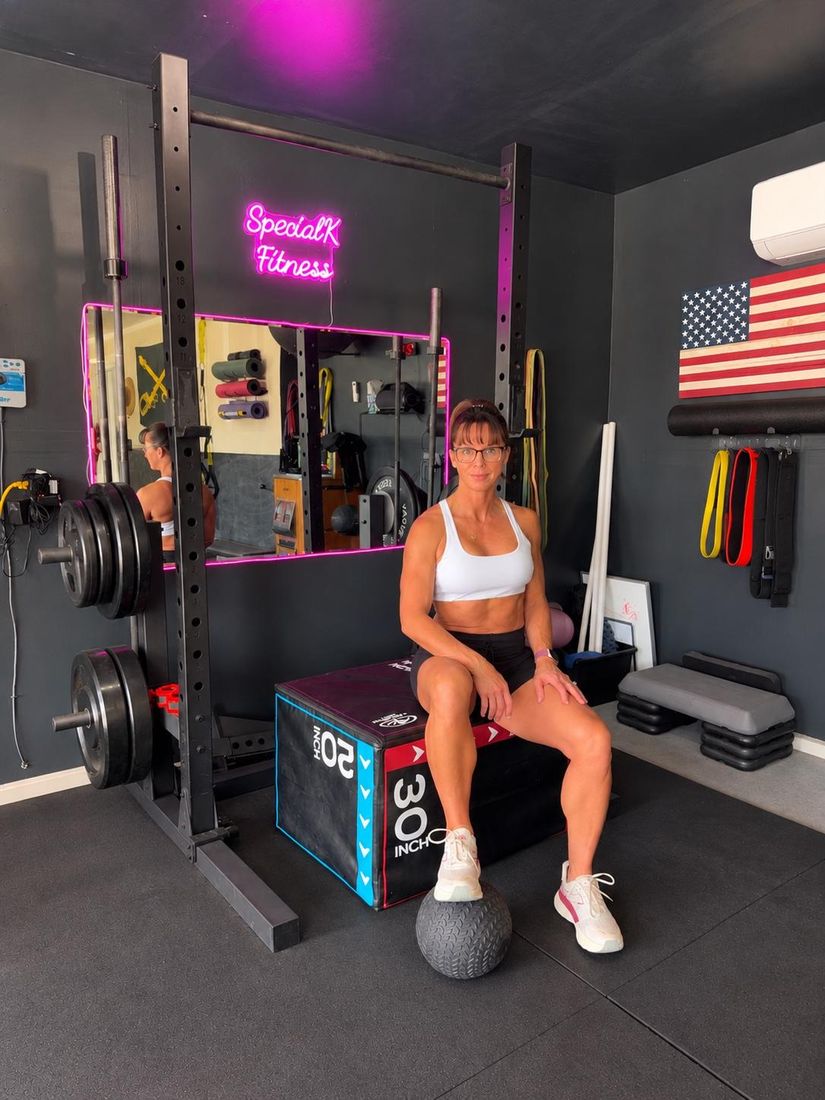 Kelli sitting on a plyo box in her studio, smiling