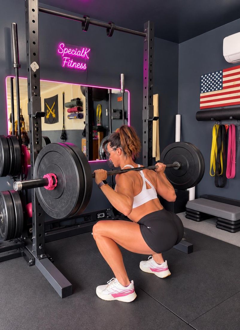 Kelli performing a barbell back squat in a squat rack