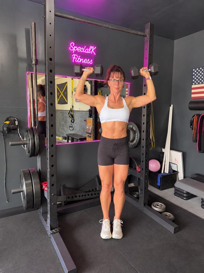 Kelli pressing two dumbbells overhead